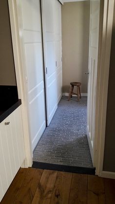 an empty hallway leading to another room with white doors and wood flooring on both sides