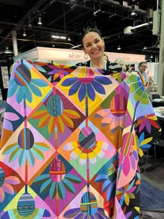 a woman is holding up a colorful piece of art that she made out of paper