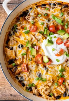 a casserole dish with chicken, tomatoes, avocado and sour cream