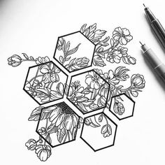 a drawing of some flowers and honeycombs on a sheet of paper next to a pen