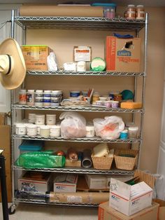 a metal shelving unit filled with lots of food and supplies next to a hat