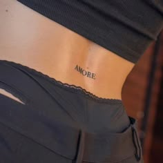 a woman's lower back tattoo with the word more on her left ribcage