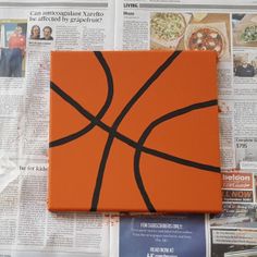 an orange box with a basketball painted on it sitting on top of newspaper pages and papers