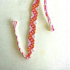 a red and white bracelet with an anchor on it's end is shown in front of a white background