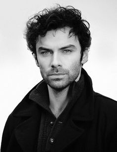 a close up of a person wearing a jacket and tie with curly hair on his head