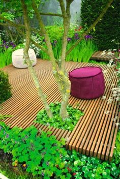 a wooden bench sitting next to a tree on top of a lush green field