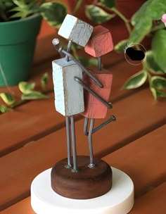 a small wooden statue is standing on a table next to some potted plants and a planter