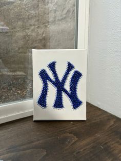 the new york yankees logo is made out of beaded beads and sits on a window sill