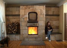 a woman standing in front of a stone fireplace