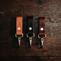 three leather key fobs on a wooden surface