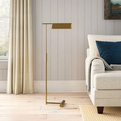 a living room with a couch, chair and floor lamp in front of a window