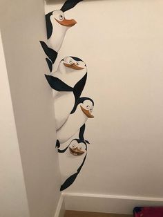 a group of penguins hanging from the side of a wall in a room with white walls