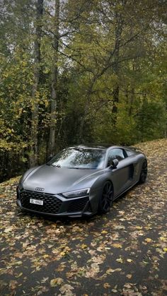 a grey sports car parked on the side of a road in front of some trees