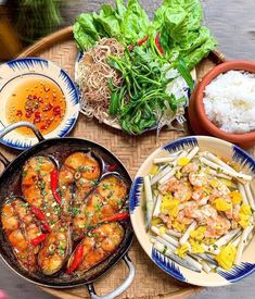 a table topped with plates of food next to rice and veggies on top of a wooden tray