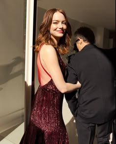 a woman in a red dress standing next to a man