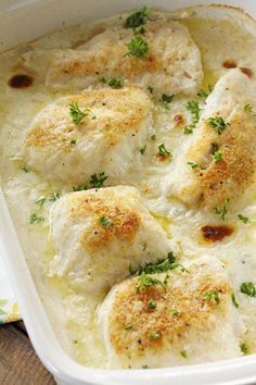 a casserole dish filled with chicken breast and gravy on top of a wooden table