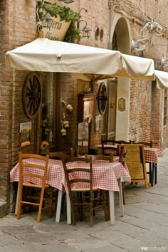 an outdoor dining area with tables, chairs and umbrellas on the side of a building