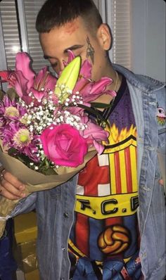 a man holding a bouquet of flowers in front of his face and wearing a denim jacket