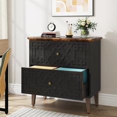 a black dresser with two drawers and a clock on the wall above it in a dining room