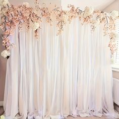 a white curtain with flowers hanging on it's side in front of a window