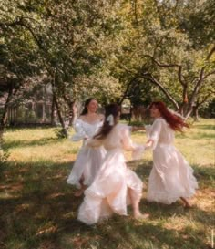 three women in white dresses are walking through the grass