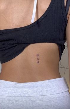 a woman's lower back with chinese writing on her left side ribcage