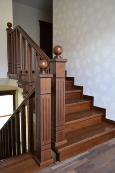 a wooden stair case next to a handrail in a room with white walls and wood floors