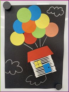 a paper house with balloons floating in the air on a black background, cut out from construction paper