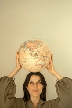 a woman holding up a large globe over her head