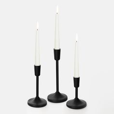 three black candlesticks with one white candle on each side and the other black