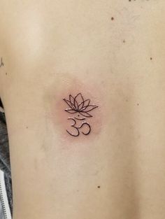 a small tattoo on the back of a woman's stomach that has a lotus flower in it