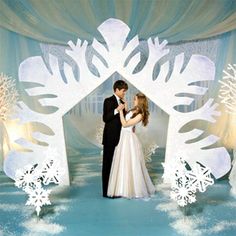 a bride and groom standing in front of a snowflake backdrop