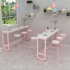 a table and chairs in a room with pink accents on the walls, along with hanging lights