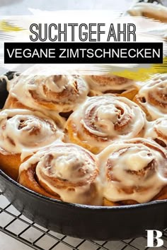 a pan filled with cinnamon buns covered in icing on top of a cooling rack