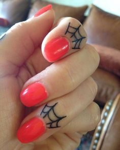 a woman's hand with a spider web design on her fingers and red nail polish