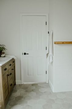 a bathroom with white walls and tile flooring next to a wooden cabinet in the corner