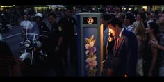 a group of people standing next to each other in front of a phone booth with flowers on it