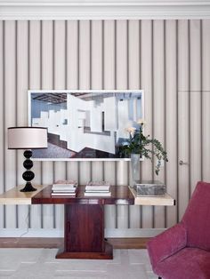 a living room with striped wallpaper and a red chair