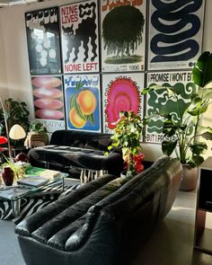 a living room filled with black furniture and lots of posters on the wall behind it