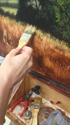 a person holding a brush in front of a painting