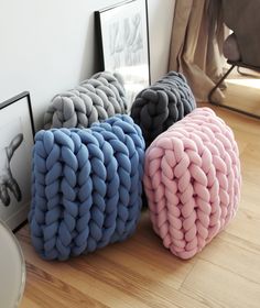 three different colored knitted pillows sitting on the floor next to pictures and framed photographs