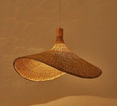 a woven lamp hanging from a ceiling in a room with beige walls and flooring