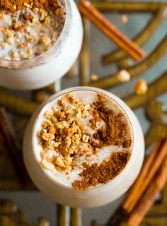 two glasses filled with different types of food on top of a table next to cinnamon sticks