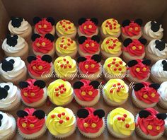 mickey mouse cupcakes are arranged in a box with red and yellow frosting