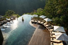 an outdoor swimming pool with umbrellas and lounge chairs on the deck overlooking the water