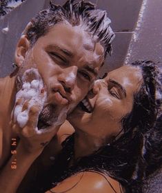 a man and woman are brushing their teeth in front of a mirror with soap on them