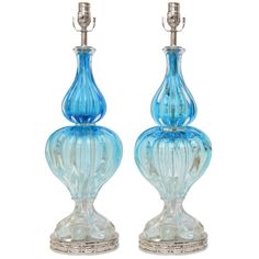 two blue glass vases sitting next to each other on top of a metal stand