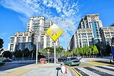 a yellow street sign sitting on the side of a road next to tall buildings and traffic lights