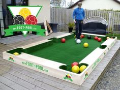 a man standing on top of a green pool with balls in it and a foo - poo sign