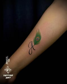 a peacock feather with the letter a on it's left forearm tattoo by tattoo art